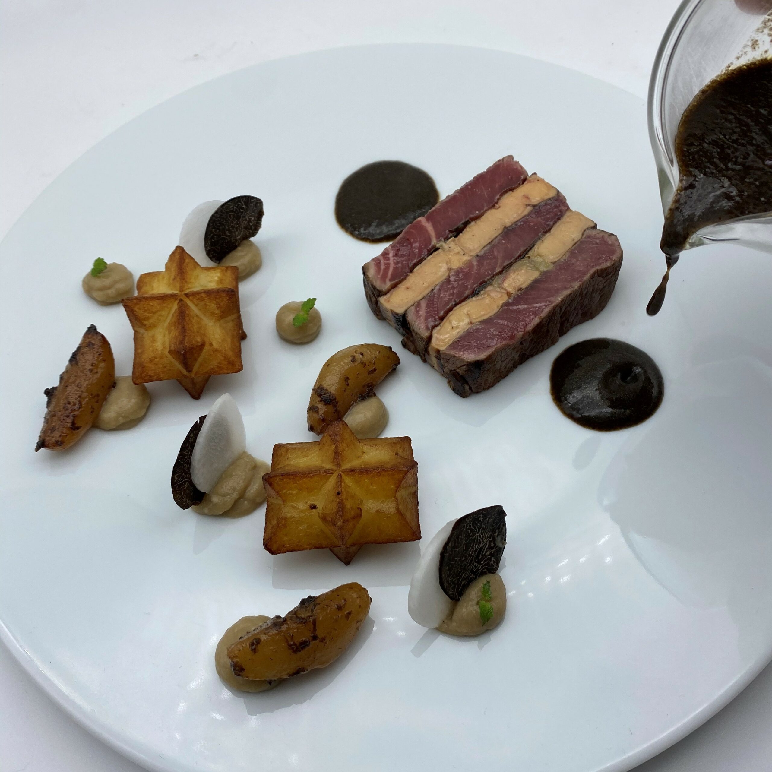 Pressé de filet de boeuf Rossini, purée de topinambours rôtis, navets glacés au caramel de truffe, pommes diamant et jus périlleux